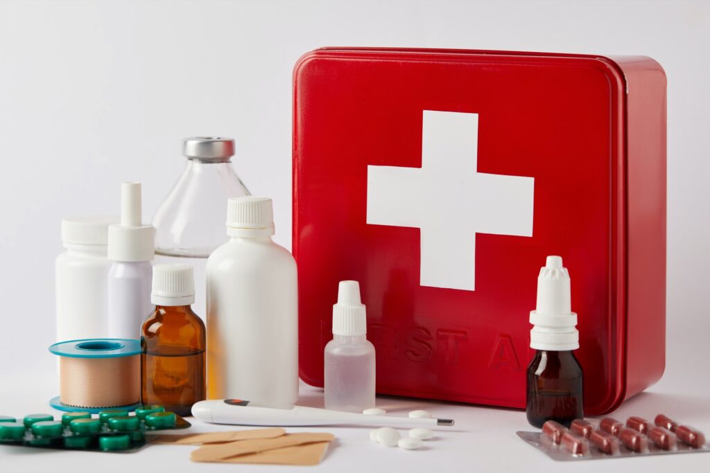 close-up shot of first aid kit box with different medical bottles and supplies on white