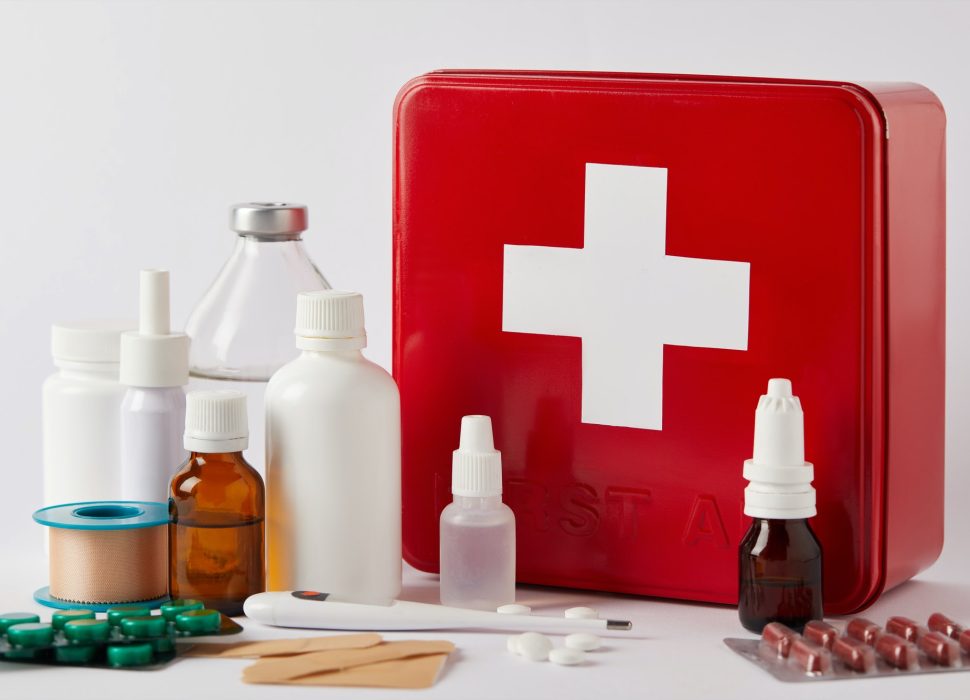 close-up shot of first aid kit box with different medical bottles and supplies on white