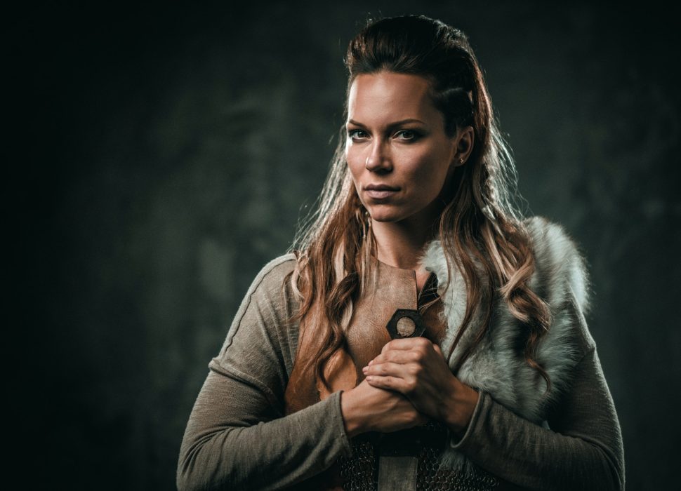 Viking woman with cold weapon in a traditional warrior clothes